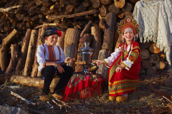 Сестра и брат в русских народных костюмах сидит возле Самовар и смеется — стоковое фото