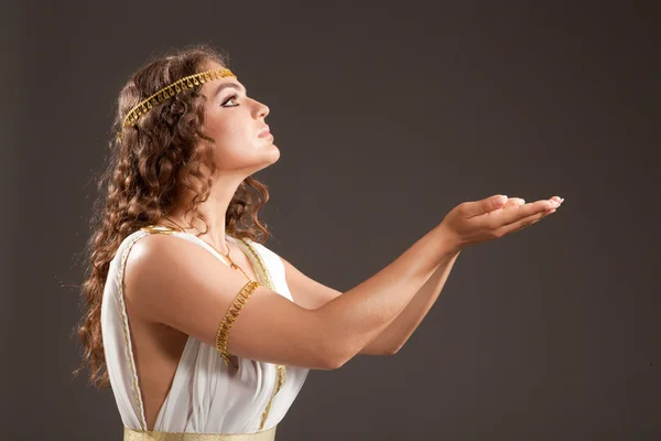 Классическая греческая богиня в тунике, несущей что-то на ее руках — стоковое фото