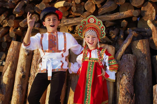 Два российских детей в русские народные костюмы мальчик и девочка танцует вместе и эмоционально улыбается — стоковое фото