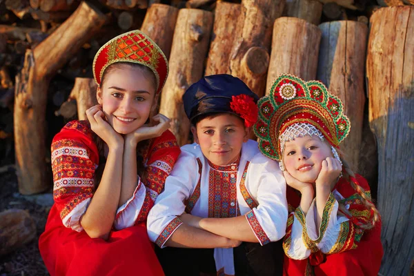 Три российских детей в русские народные костюмы, мальчик и девочка, играя вместе и эмоционально улыбается — стоковое фото