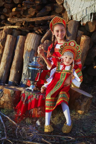 Красивая девушка в русский народный костюм сидит возле Самовар и улыбается — стоковое фото